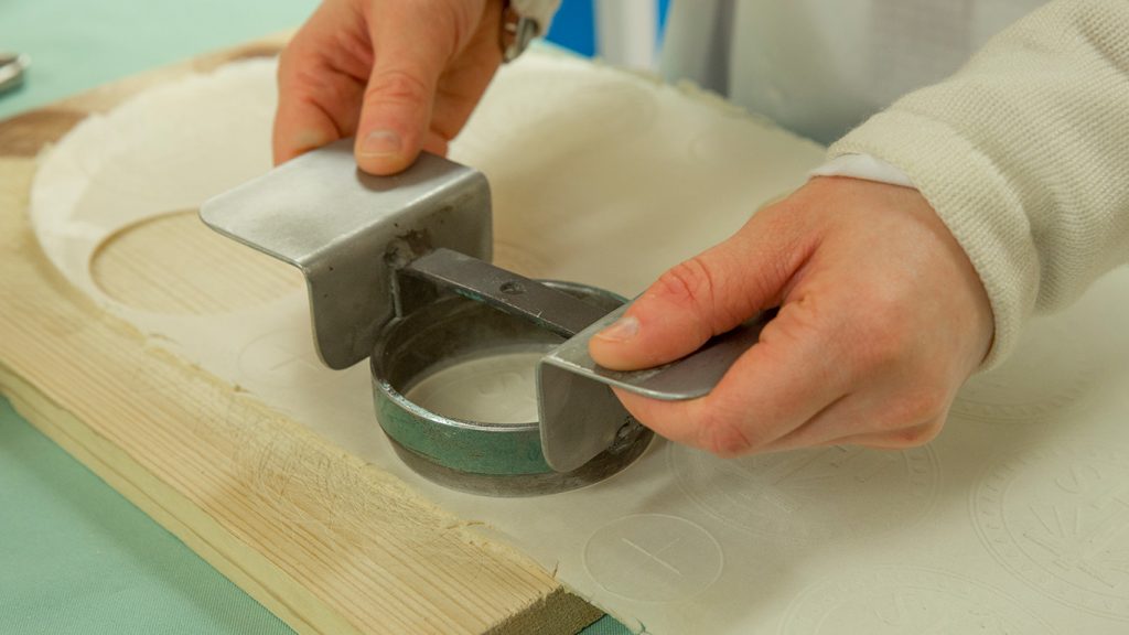 Sister using a press to make hosts